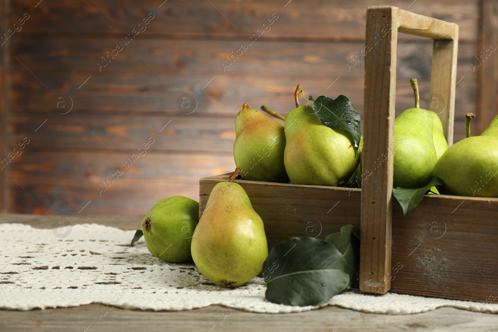 Photo of Crate with fresh green pears and leaves on wooden table, closeup. Space for text