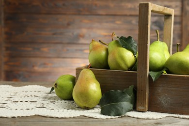 Photo of Crate with fresh green pears and leaves on wooden table, closeup. Space for text