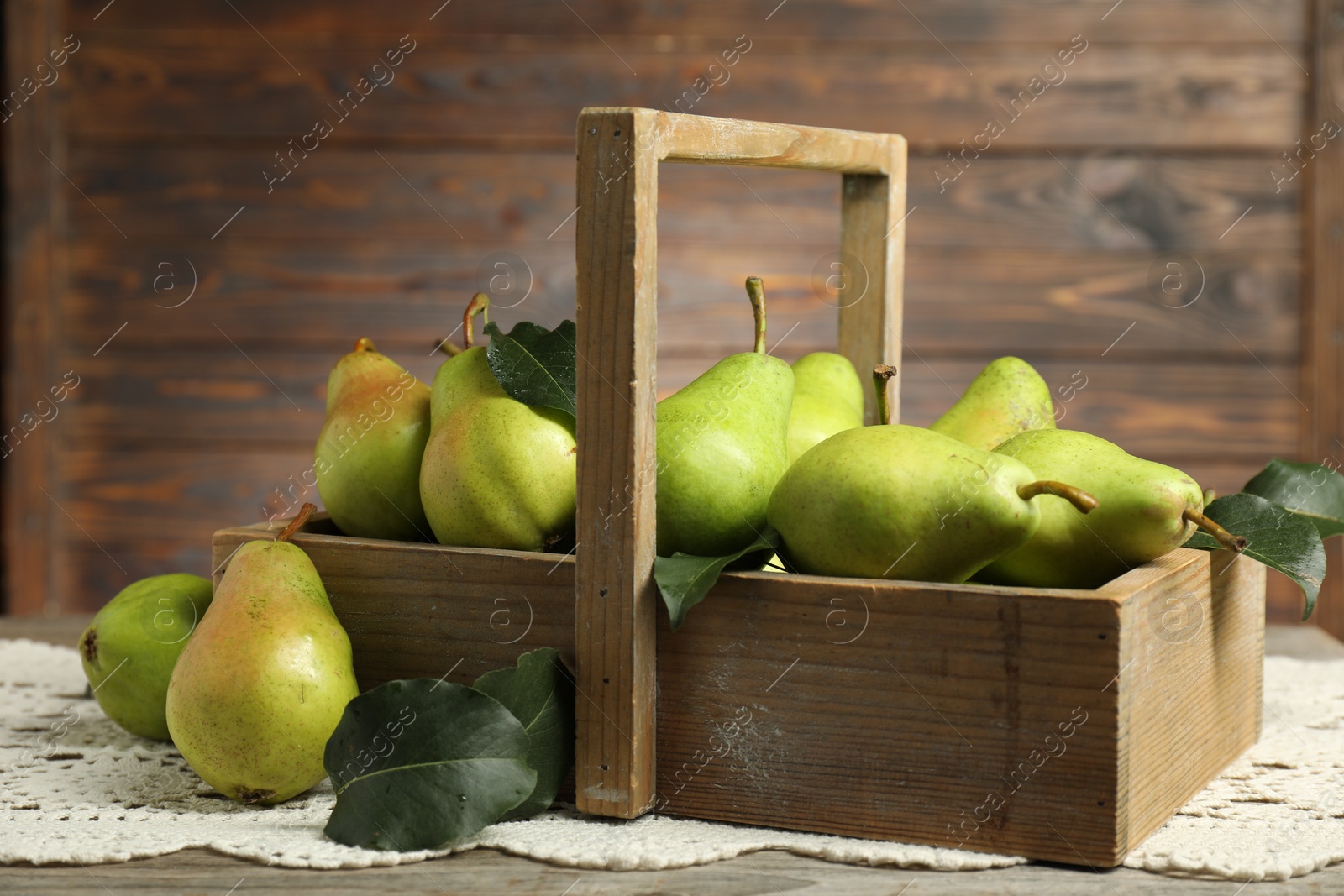 Photo of Crate with fresh green pears and leaves on wooden table, closeup