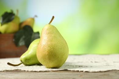 Photo of Fresh pears with water drops on wooden table against blurred green background, closeup. Space for text