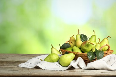 Photo of Fresh pears and leaves with water drops on wooden table against blurred green background. Space for text