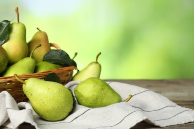 Photo of Fresh pears and leaves with water drops on wooden table against blurred green background, closeup. Space for text