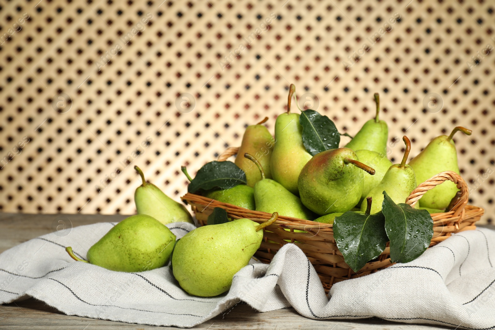 Photo of Fresh green pears and leaves with water drops on wooden table. Space for text