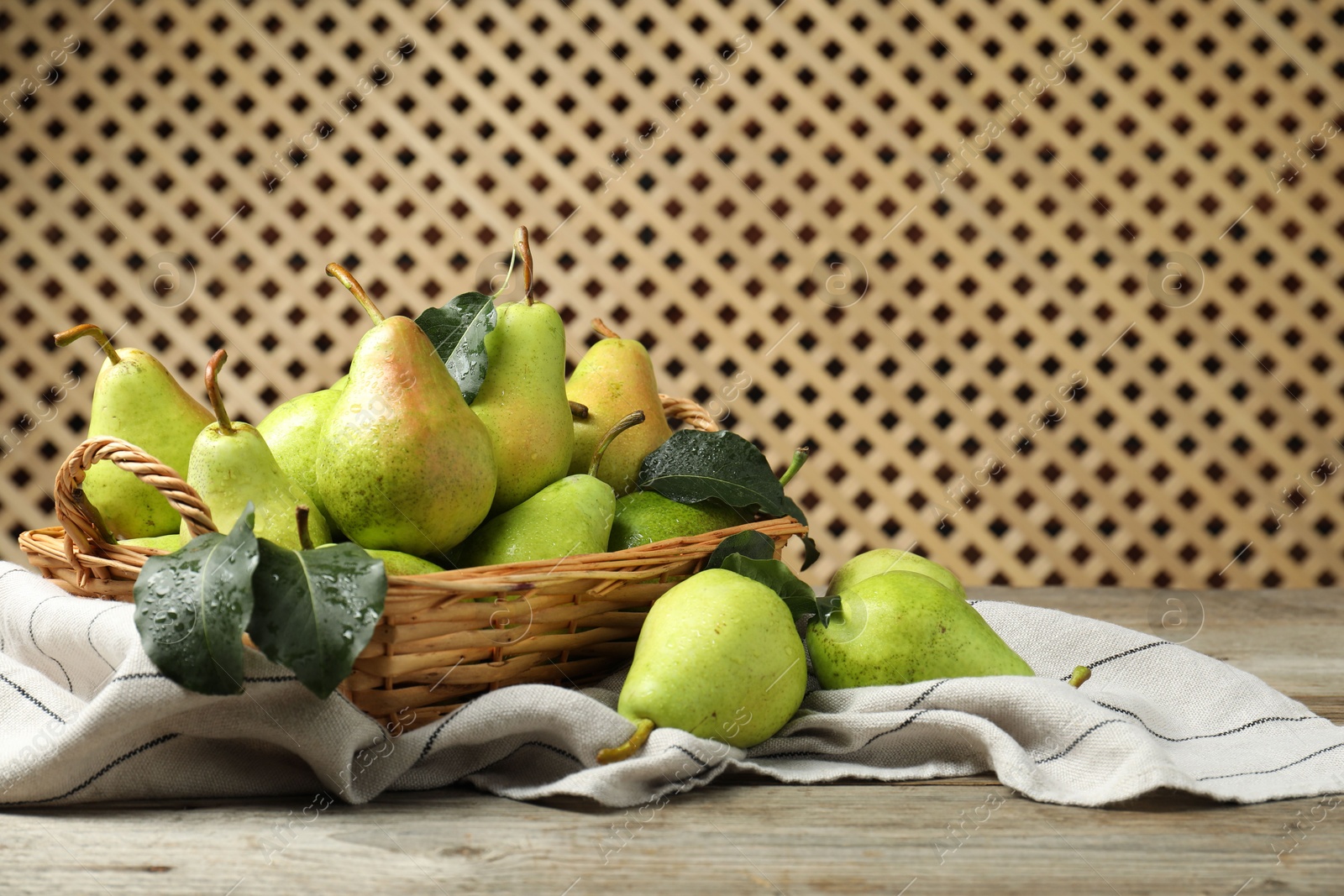 Photo of Fresh green pears and leaves with water drops on wooden table. Space for text