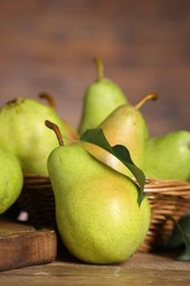 Photo of Fresh green pears and leaf on wooden table, closeup