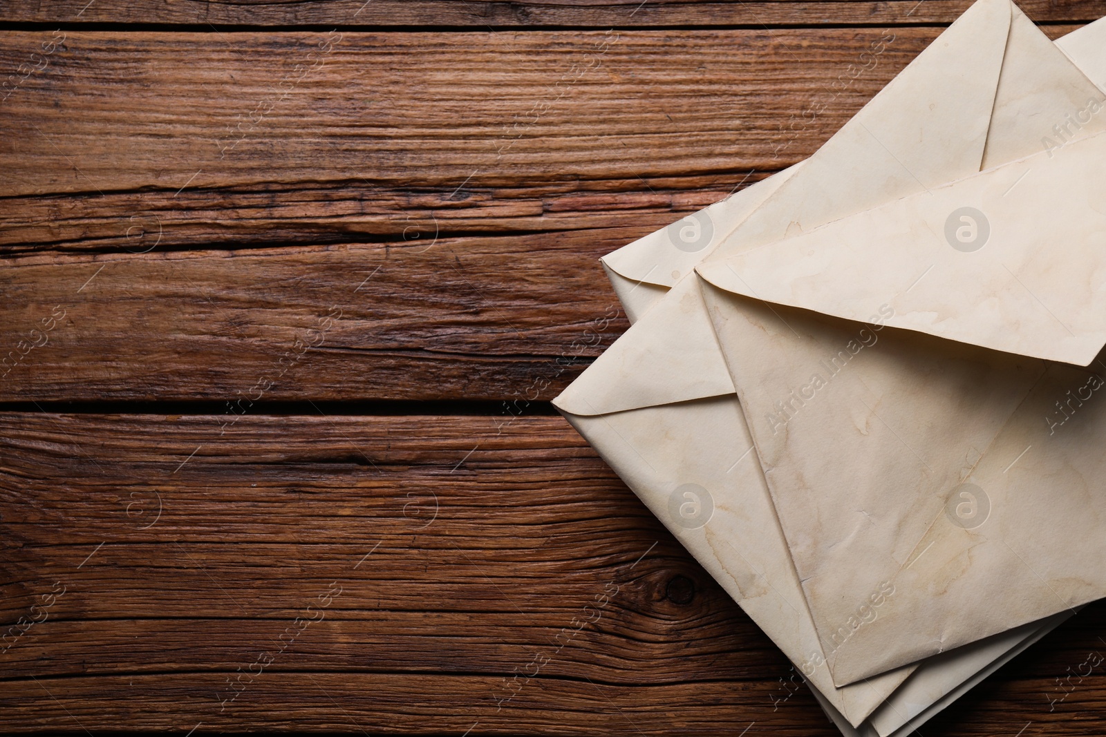 Photo of Old letter envelopes on wooden table, top view. Space for text