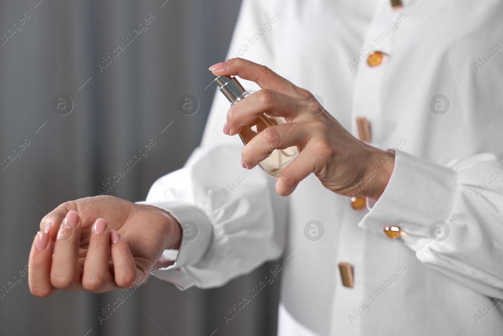 Photo of Woman spraying perfume onto wrist indoors, closeup