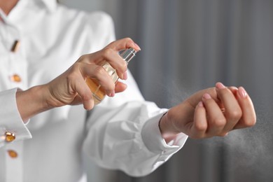 Photo of Woman spraying perfume onto wrist indoors, closeup