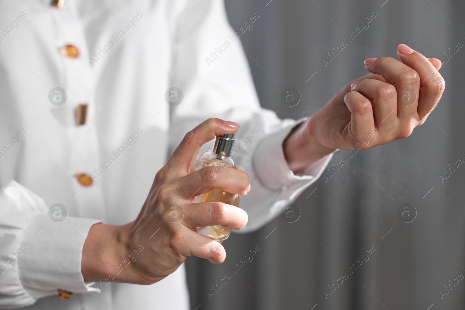 Photo of Woman spraying perfume onto wrist indoors, closeup