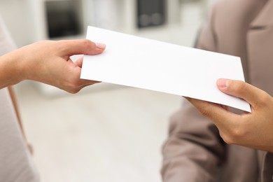 Employee receiving envelope with salary from boss in office, closeup