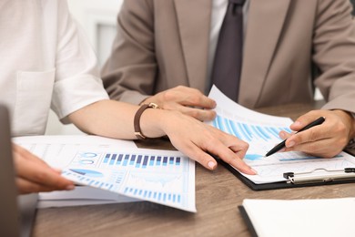 Consultant working with client at wooden table in office, closeup. Business meeting