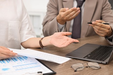 Photo of Consultant working with client at wooden table in office, closeup. Business meeting