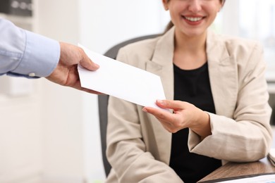 Smiling employee receiving envelope with salary from boss in office, closeup