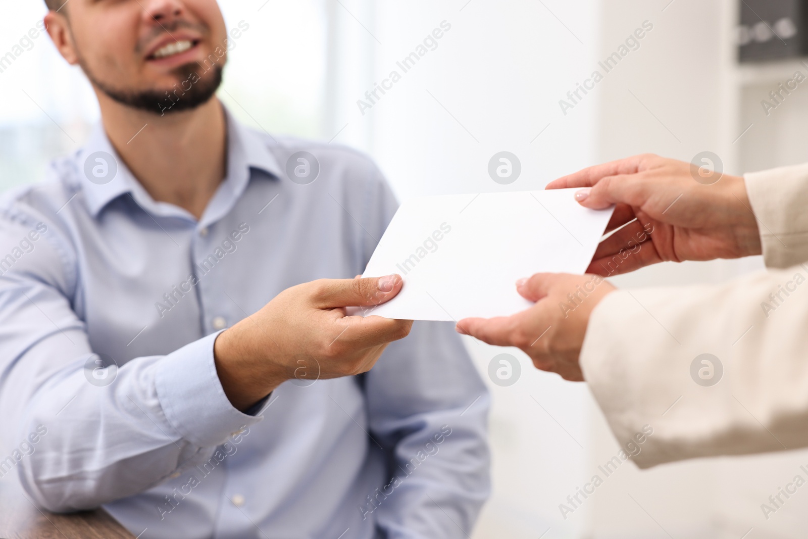 Photo of Employee receiving envelope with salary from boss in office, closeup