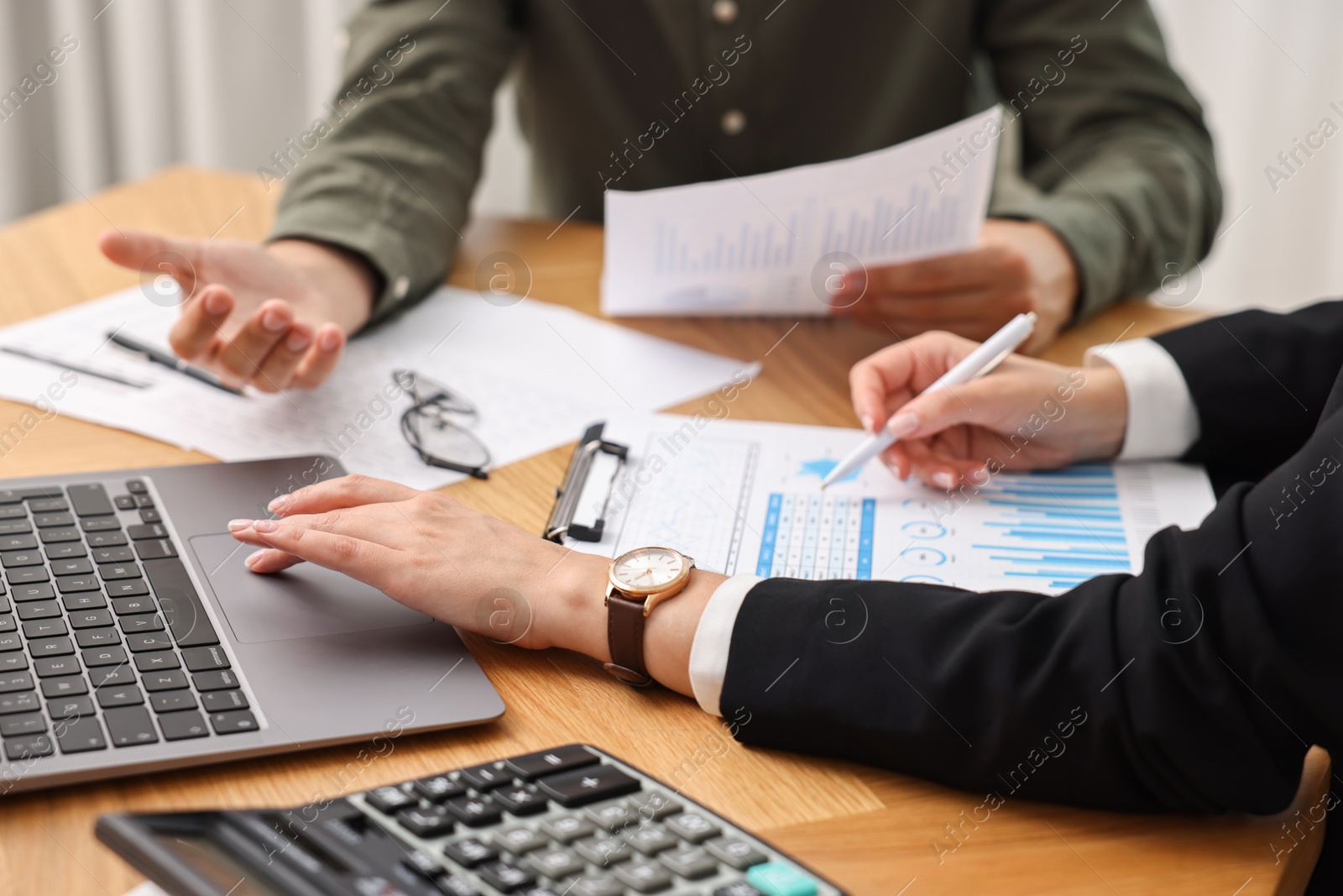 Photo of Consultant working with client at wooden table in office, closeup. Business meeting