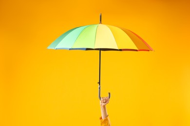 Woman with colorful umbrella on yellow background, closeup