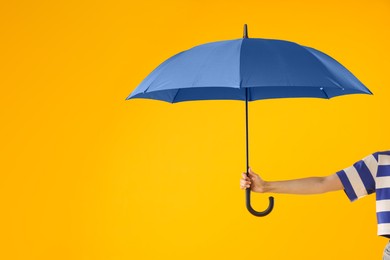 Photo of Woman with blue umbrella on yellow background, closeup