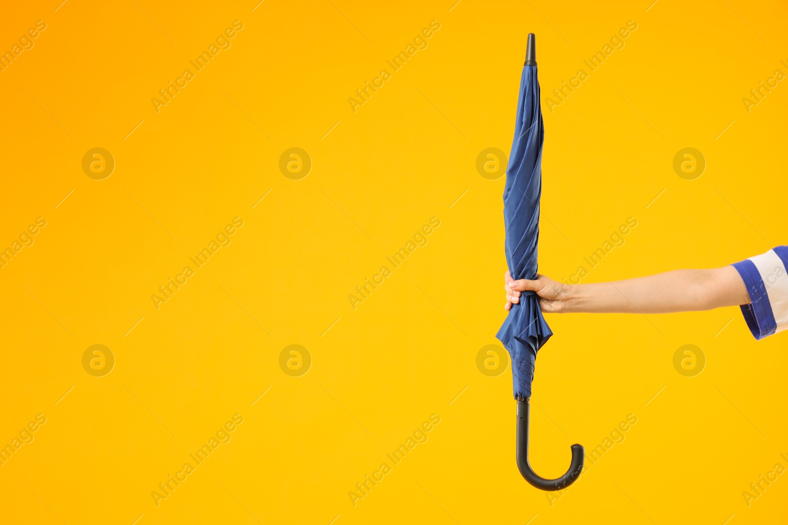 Photo of Woman with blue umbrella on yellow background, closeup. Space for text