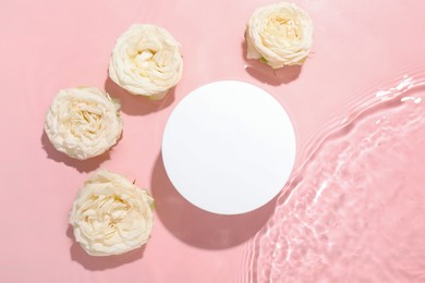 Photo of Beautiful rose flowers and round shaped podium in water on pink background, flat lay