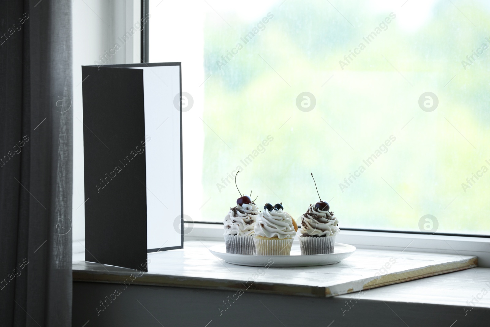 Photo of Cupcakes and light reflector on window sill in studio. Professional food photography