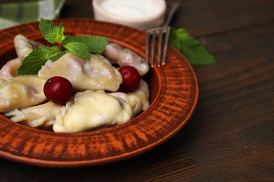 Traditional Ukrainian dumplings (varenyky) with cherries served on wooden table, closeup