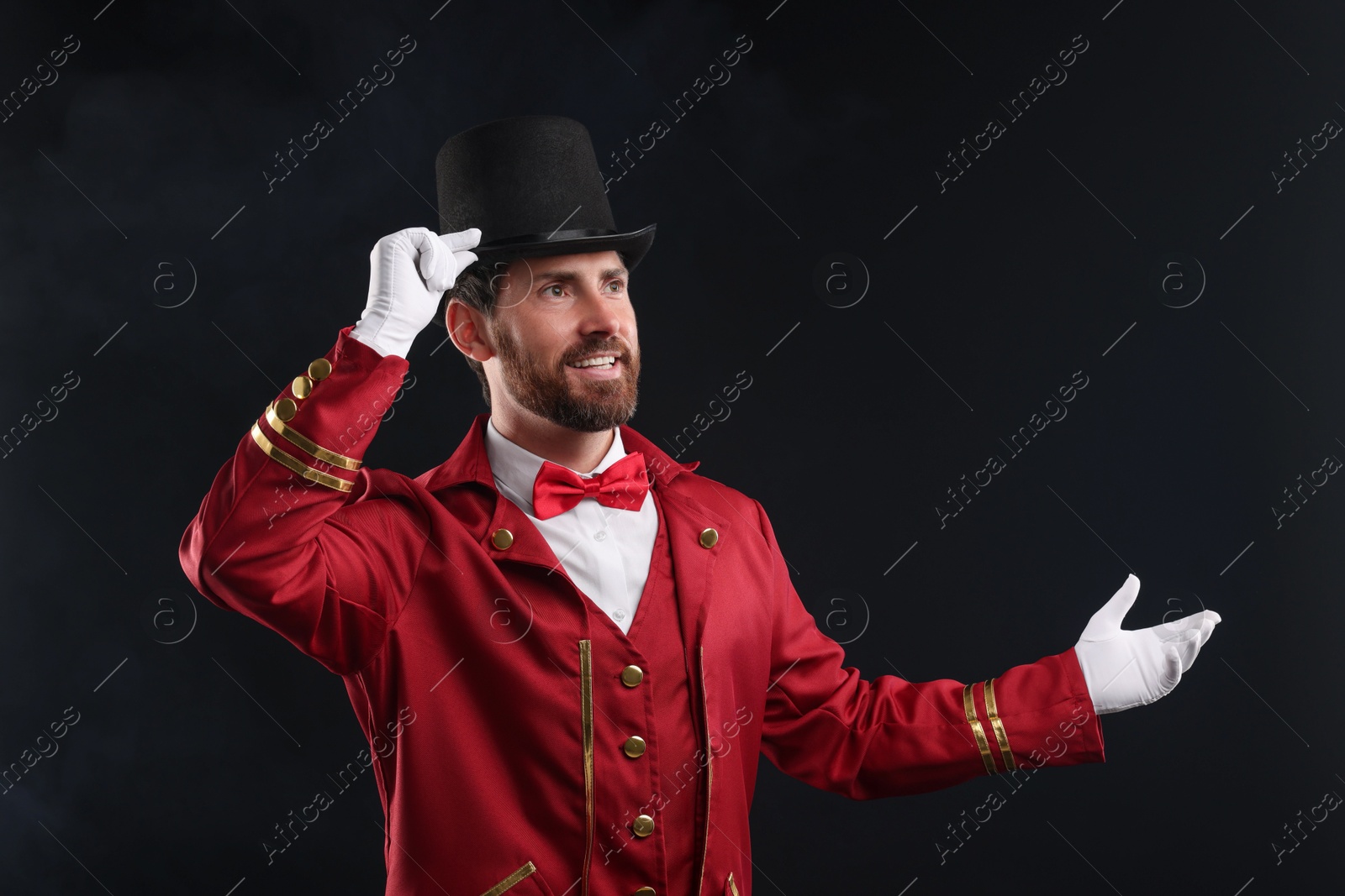 Photo of Portrait of showman in red costume and hat on black background