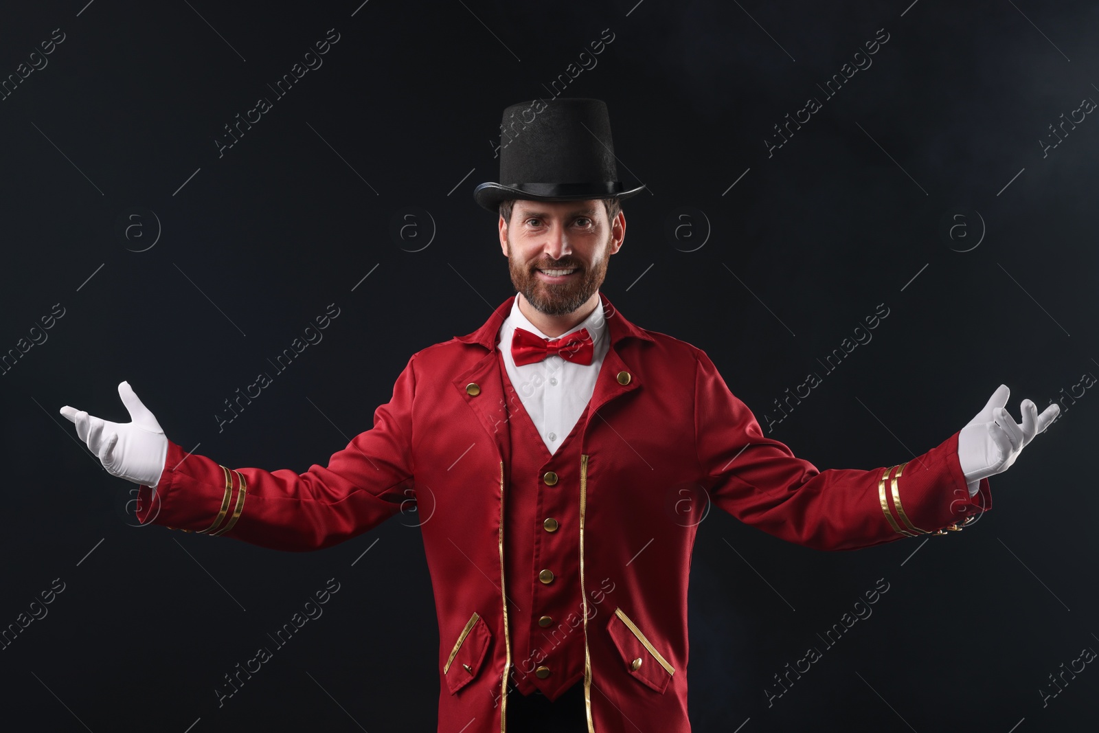 Photo of Portrait of showman in red costume and hat on black background