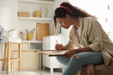 Photo of Beautiful woman drawing portrait with pencil in studio