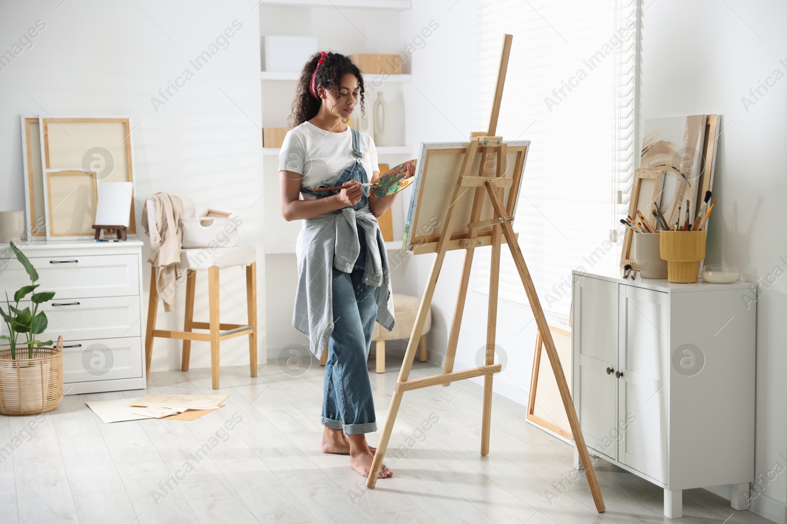 Photo of Beautiful woman drawing picture on canvas in studio