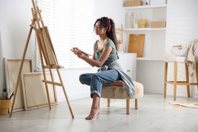 Photo of Beautiful woman drawing picture on canvas in studio