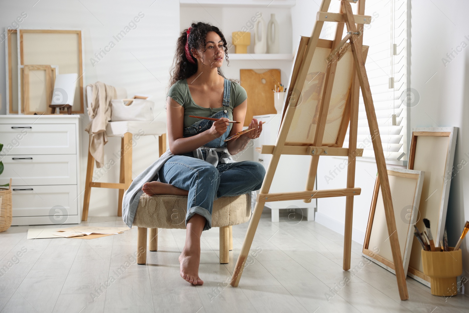 Photo of Beautiful woman drawing picture on canvas in studio