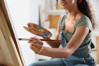 Photo of Smiling woman drawing picture with paint in studio, closeup