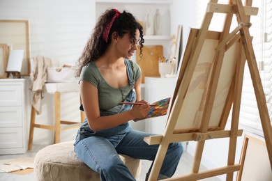 Photo of Smiling woman drawing picture on canvas in studio