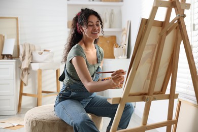 Smiling woman drawing picture on canvas in studio