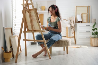 Smiling woman drawing picture on canvas in studio