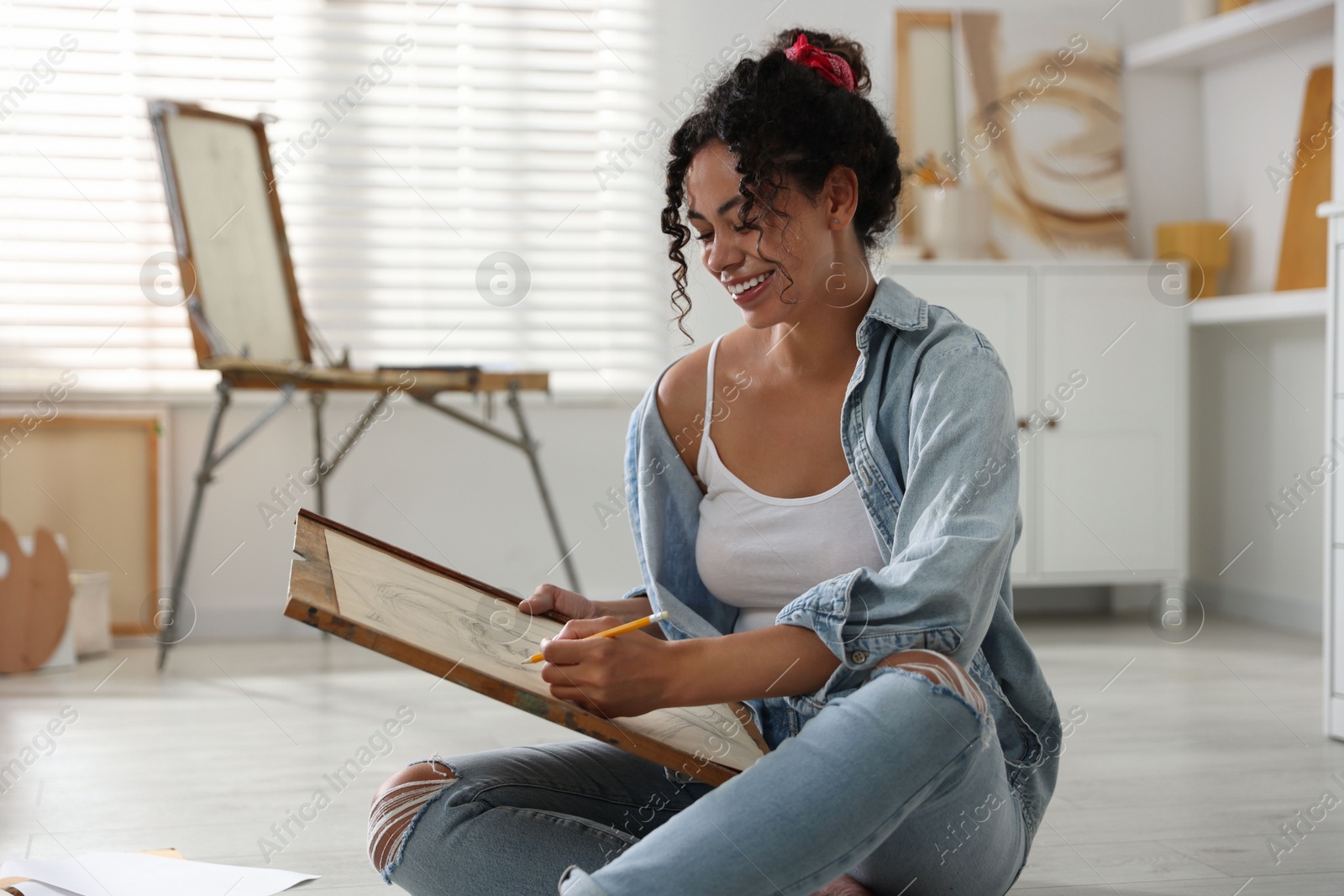 Photo of Smiling woman drawing picture with pencil in studio