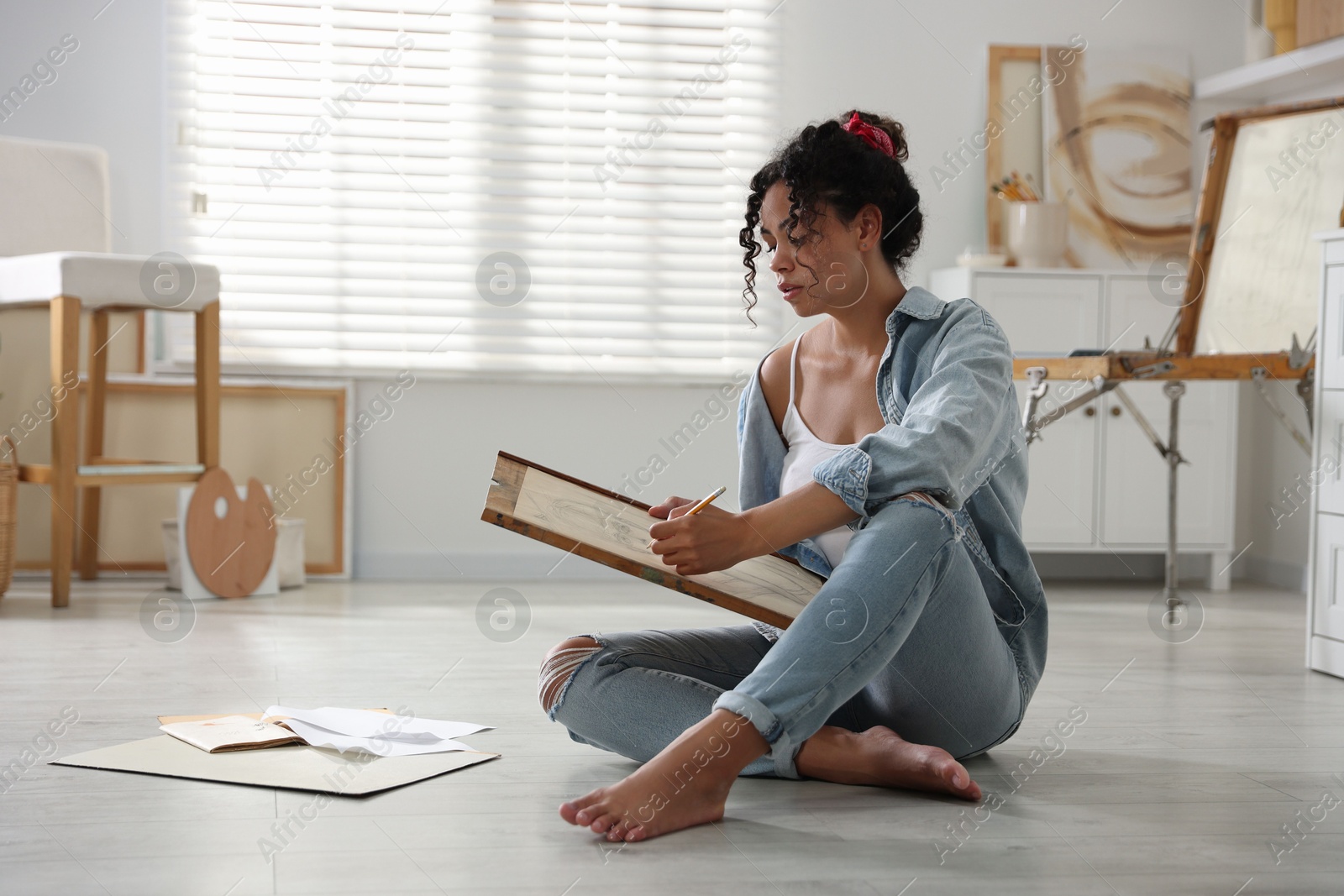 Photo of Woman drawing picture with pencil on floor in studio