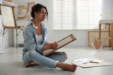 Woman drawing picture with pencil on floor in studio