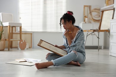 Photo of Woman drawing picture with pencil on floor in studio