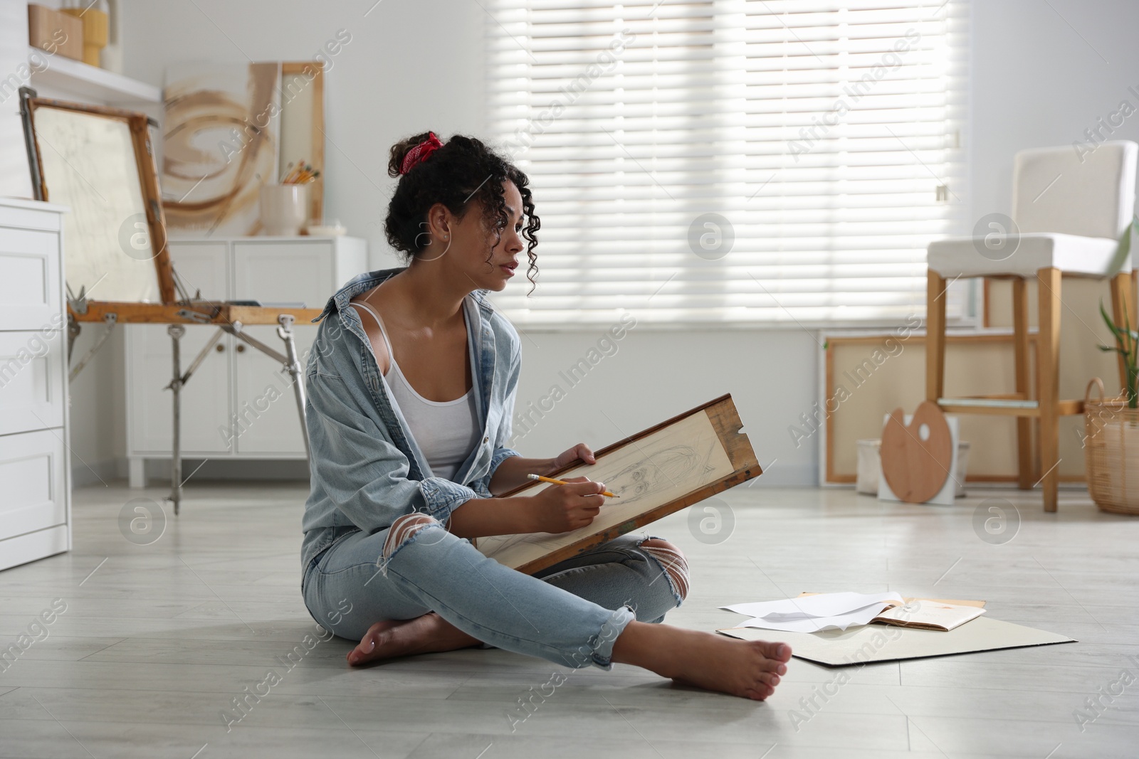 Photo of Woman drawing picture with pencil on floor in studio