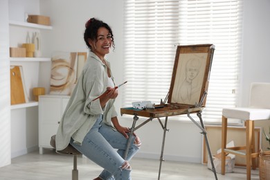 Smiling woman drawing picture on canvas in studio