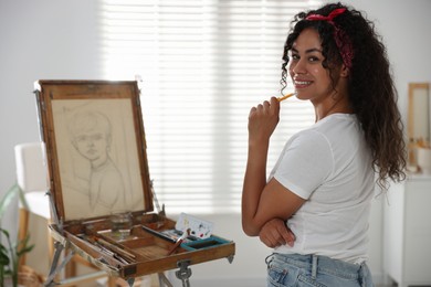 Photo of Smiling woman drawing picture with pencil in studio