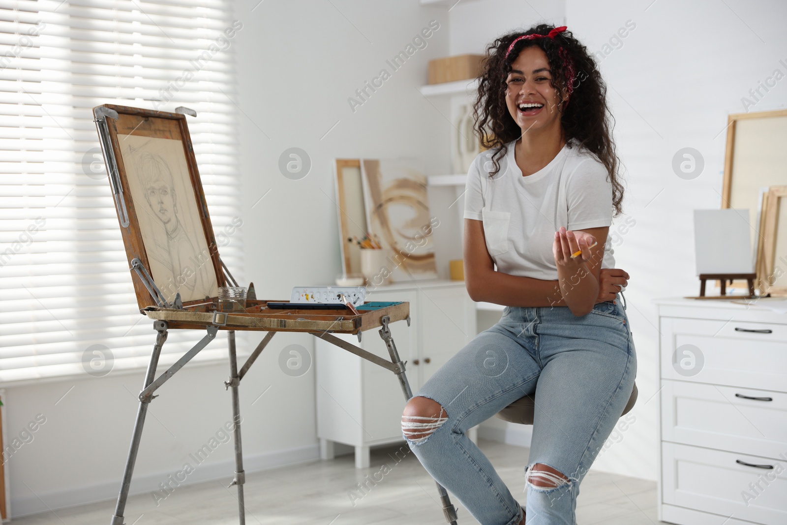 Photo of Happy woman drawing picture with pencil in studio