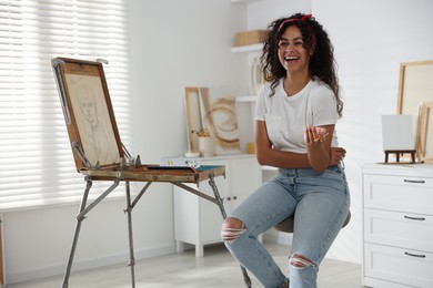 Happy woman drawing picture with pencil in studio