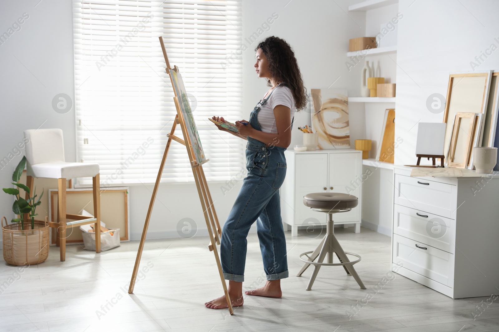 Photo of Beautiful woman drawing picture on canvas in studio