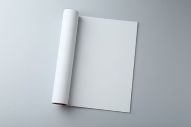 Open magazine with blank page on grey background, top view. Mockup for design