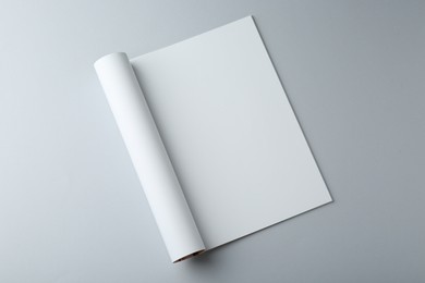 Open magazine with blank page on grey background, top view. Mockup for design