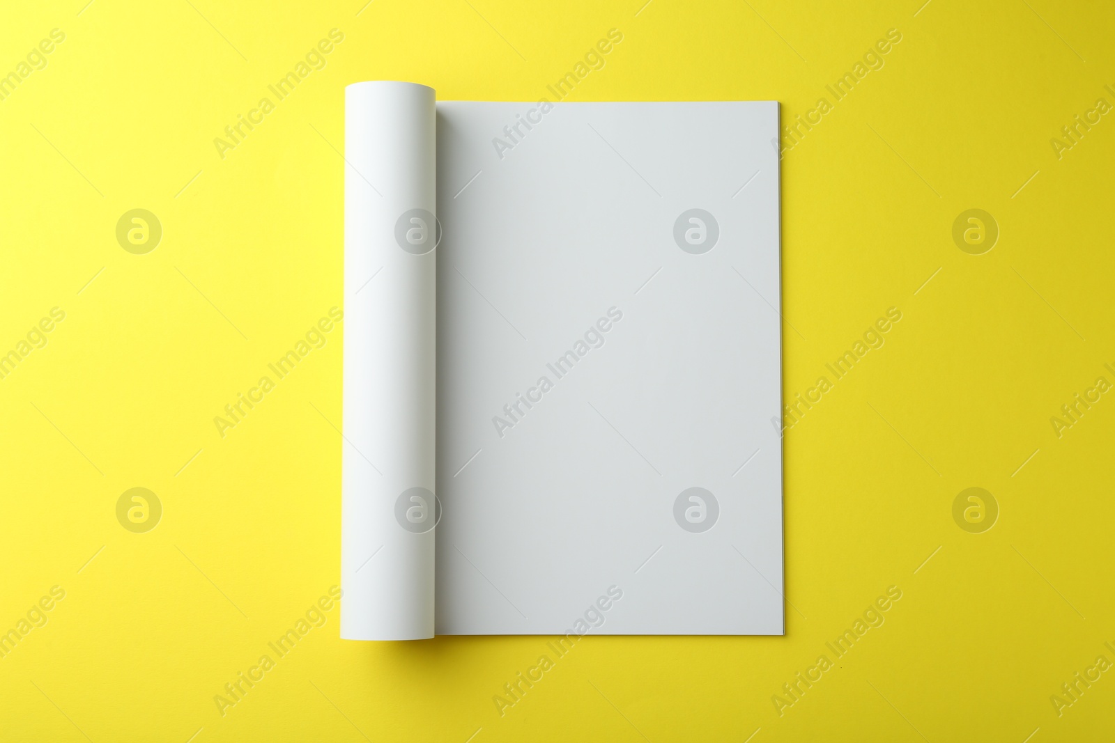 Photo of Open magazine with blank page on yellow background, top view. Mockup for design