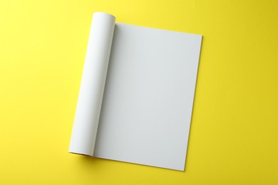 Photo of Open magazine with blank page on yellow background, top view. Mockup for design