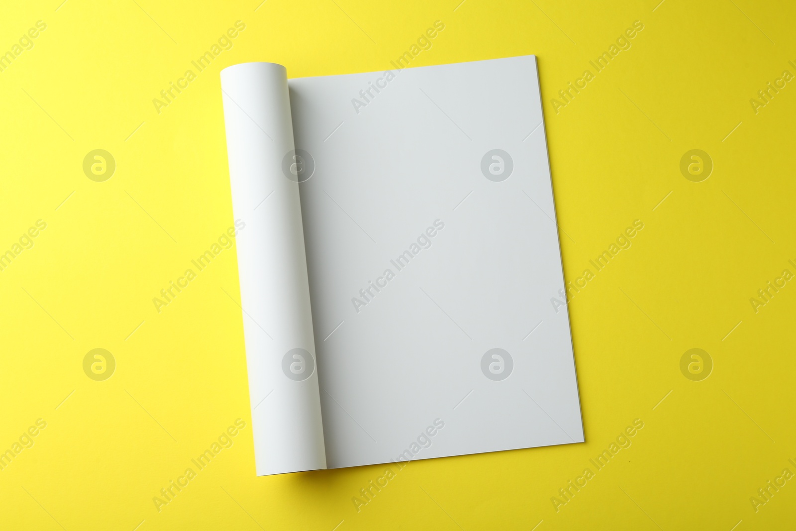 Photo of Open magazine with blank page on yellow background, top view. Mockup for design